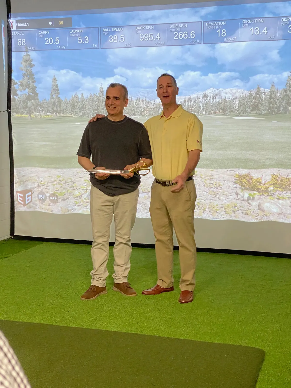 Two men standing in front of the simulator screen at the ribbon cutting