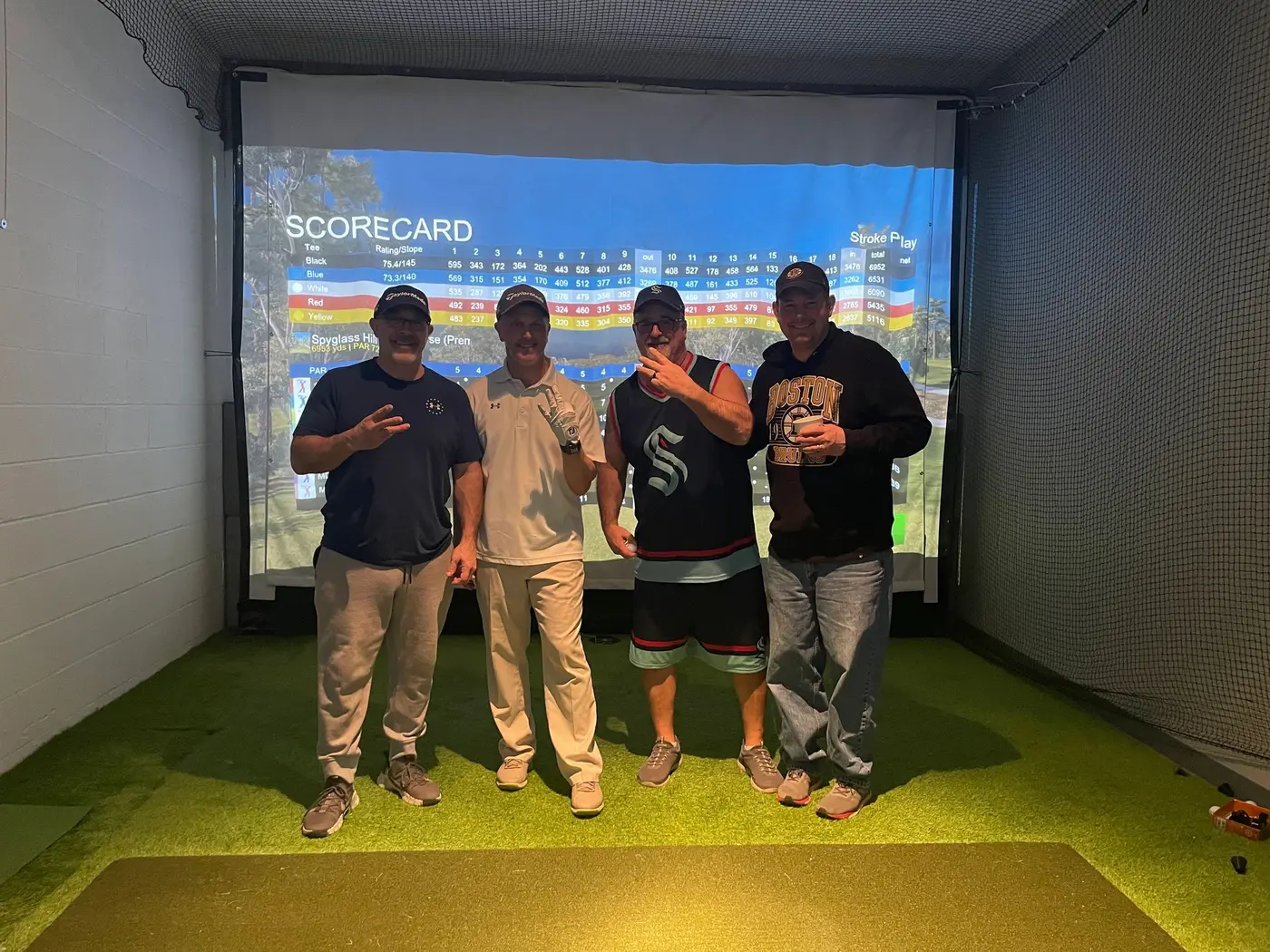 Four golfers in front of the simulator scorecard after their round