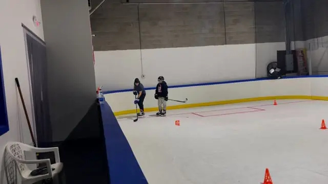 A coach working with a young player on the ice