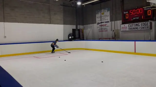 A young player shooting on the ice